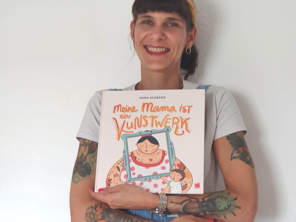 Jeder Mensch ist besonders und einzigartig - egal ob mit oder ohne Tattoo. Doch die bunten Bilder, die mache Erwachsene auf ihrem Körper haben, sind schon faszinierend. Eben echte Kunst! Doch nicht jede:r sieht das so. "Meine Mama ist ein Kunstwerk" von Hana Acabado ist eine wahre Liebeserklärung an alle tätowierten Mamas und zeigt, wie vielfältig unsere Körper sein können. Ein Appell für Diversität und Toleranz. Denn: Ob tätowiert oder nicht, alle Menschen sind Kunstwerke und sollten für das gefeiert werden, was sie sind.