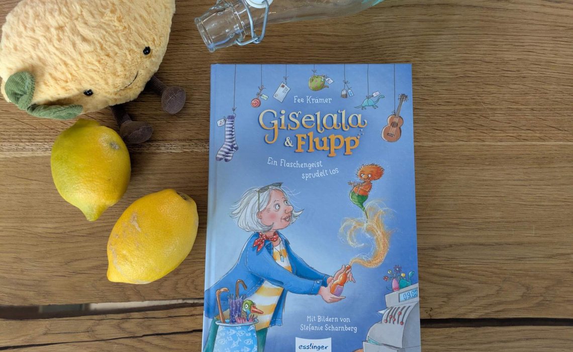 Cover von Giselala und Flupp auf Holz mit Zitronen und Limoflasche als Deko.